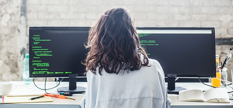 Woman working at a desk with two monitors