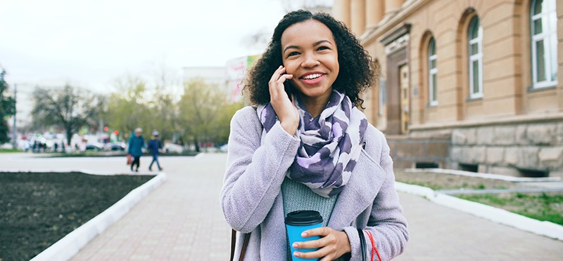 Happy woman walking and talking on a cellphone.