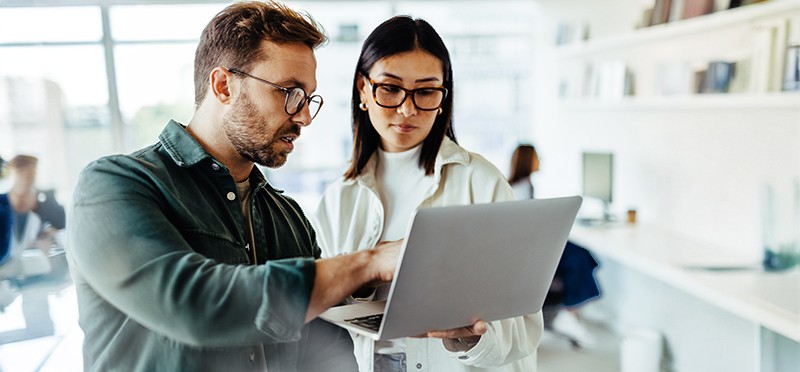 Man and woman in an office looking at a laptop