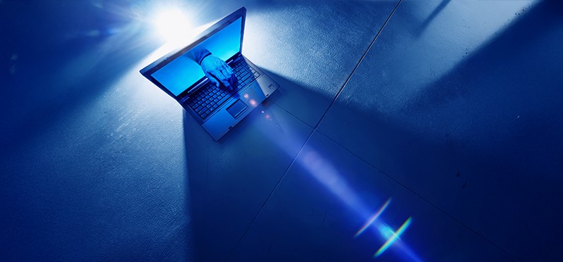 A hand coming out of a laptop screen and typing on the keyboard