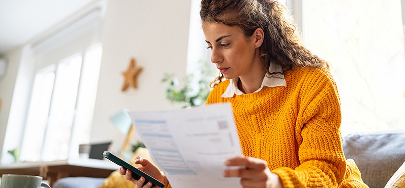 Woman looking at a paper form and her smartphone
