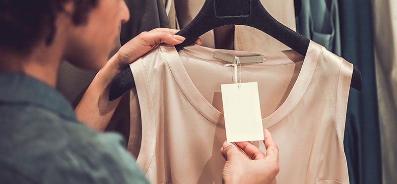Closeup of a woman's hand checking the price tag on a shirt in a store