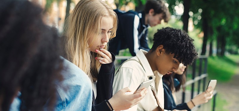 A young man and young woman looking at their smartphones