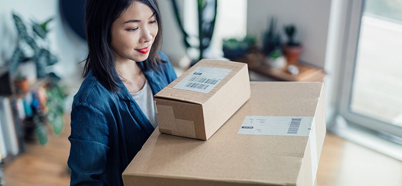Woman holding two packages in cardboard boxes