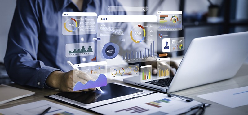 Charts and graphs hovering over a laptop someone is working on