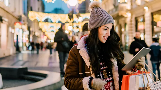 Woman with shopping bags, looking at a tablet in a shopping mall