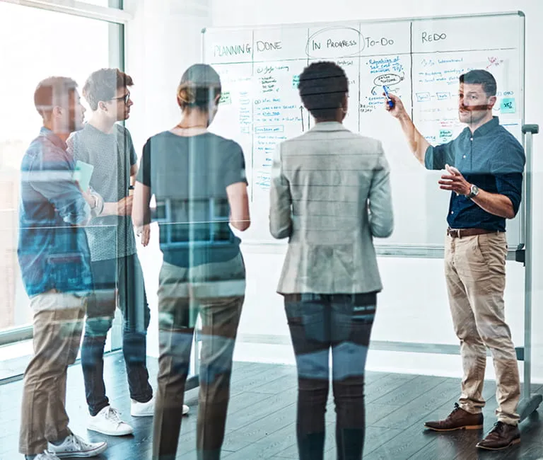 Group of employees standing next to a white board