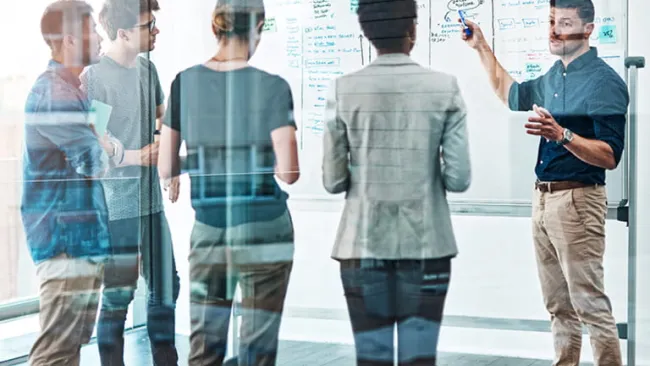 Group of employees standing next to a white board