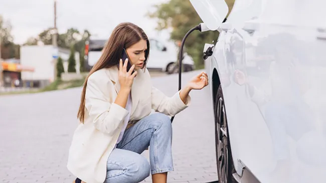 Woman kneeling near an electric car that's charging