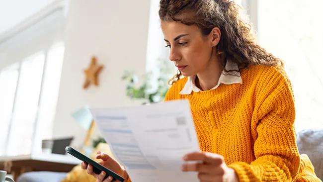 Woman looking at a paper form and her smartphone