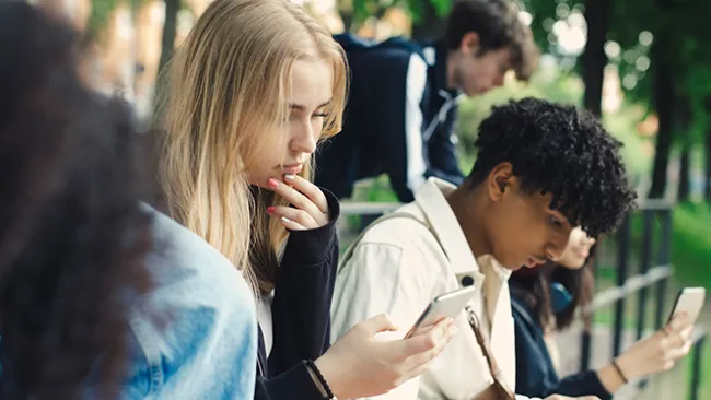 A young man and young woman looking at their smartphones