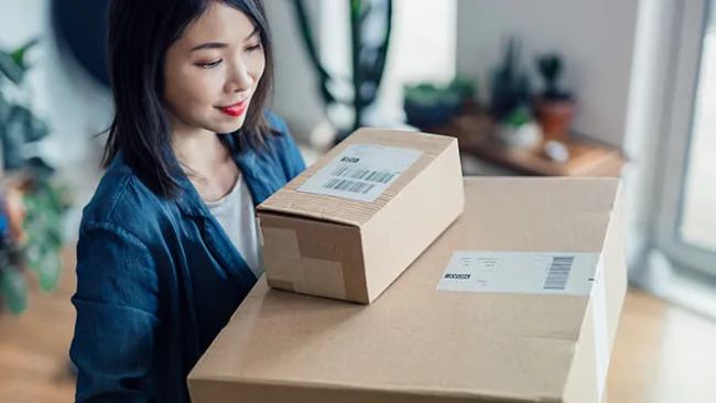 Woman holding two packages in cardboard boxes
