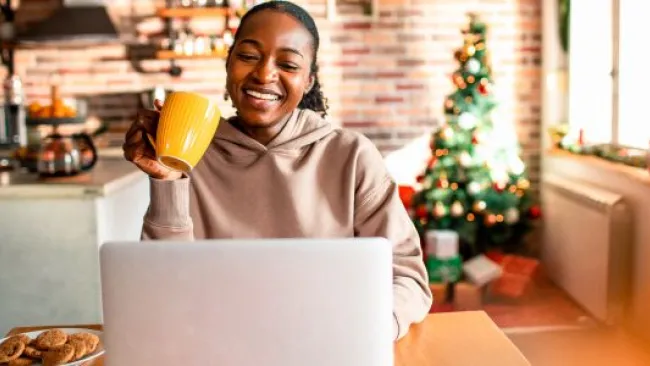 A woman holding a mug while looking at her laptop