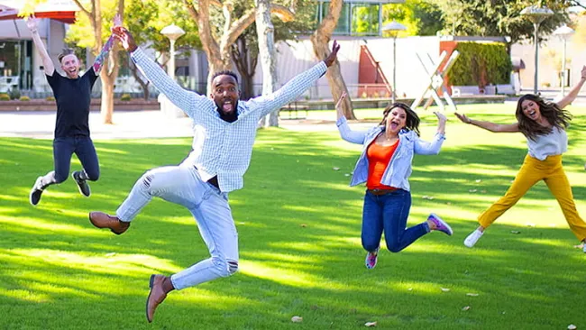 Group of people in a field jumping in celebration
