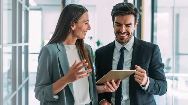 Coworkers smiling while looking at a tablet