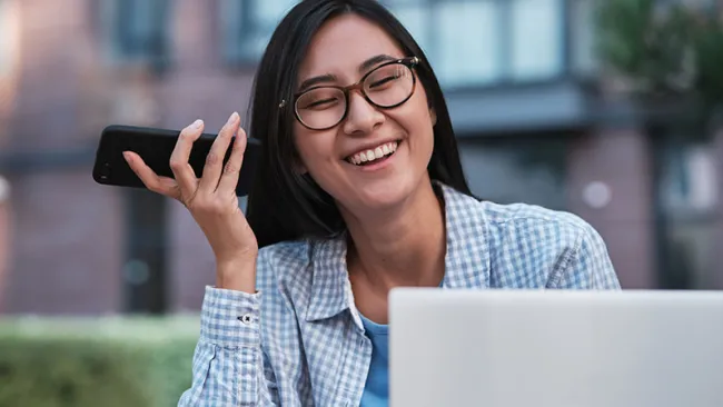 A happy customer speaking on the phone while using her computer