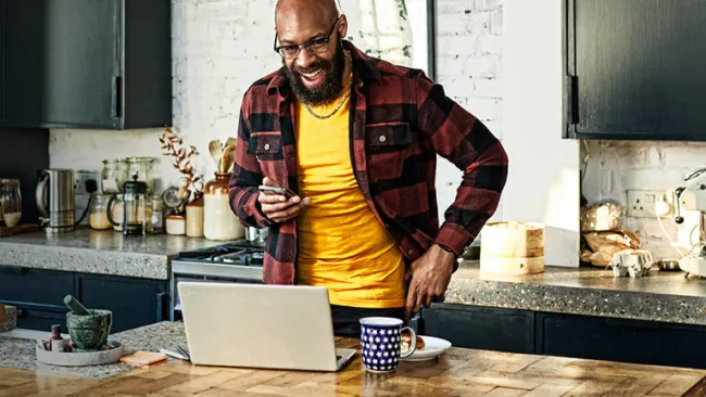 Customer Experience Strategy masthead with man in kitchen using laptop