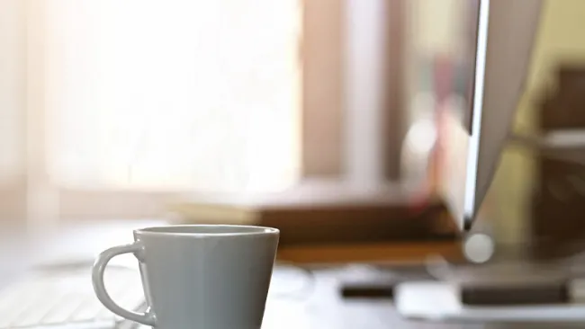 A home office desk with computer and coffee cup on it