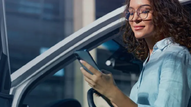 Woman sitting in her car using her phone