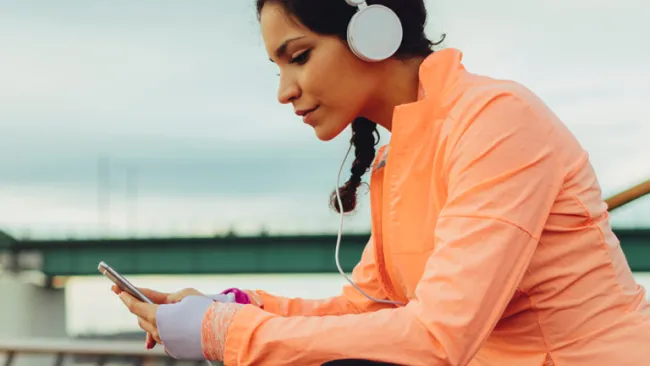 Woman sitting on bench using her phone with earphones