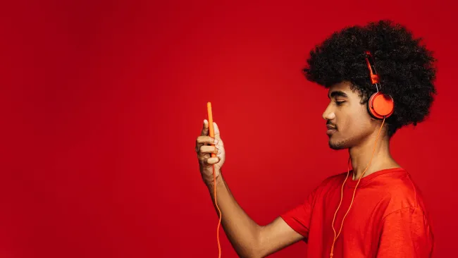 Man wearing headphones and looking left at his phone