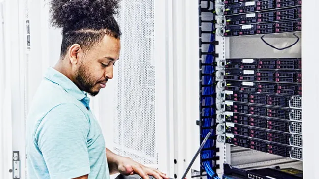 Man working on a laptop in a data center