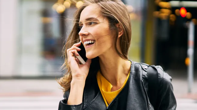 Woman on her phone walking across a sidewalk