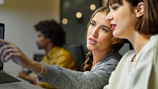 Two women discussing what's on a computer screen