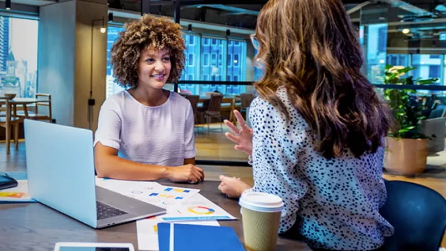 Two people having a discussion in an open office setting
