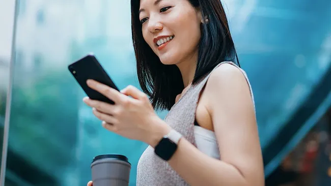 Woman using her phone near a large window
