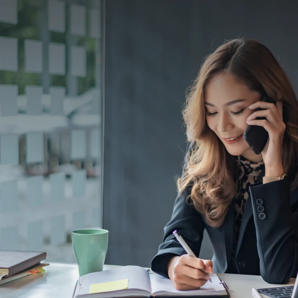 Woman taking notes while talking on the phone