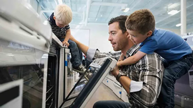 A father and his two young sons shopping for an oven